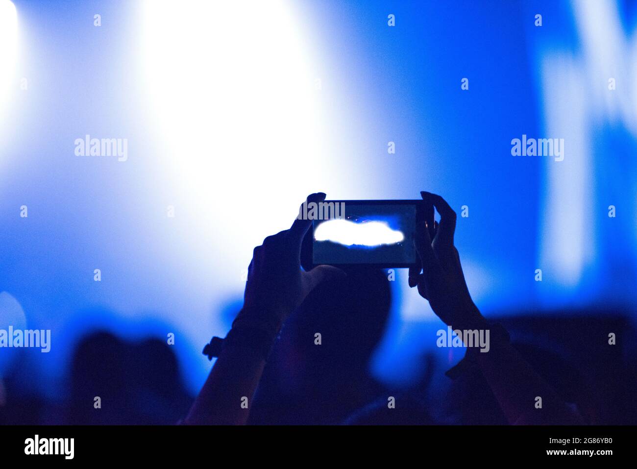 Tenere a mano lo smartphone al festival della musica dal vivo. Luci da concerto sul mirino Foto Stock