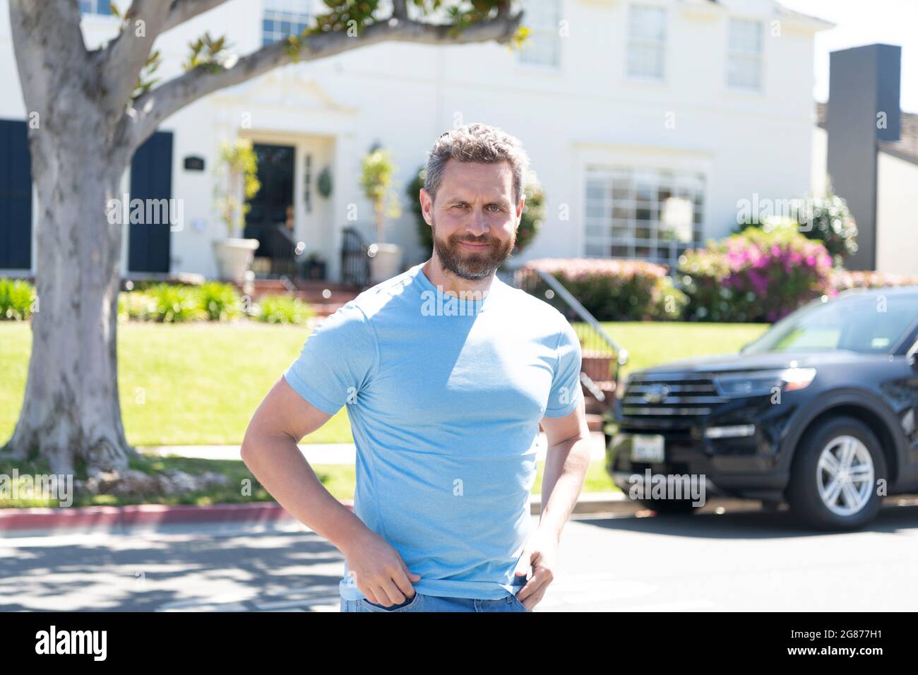 uomo sorridente bearded in camicia blu casual all'aperto a casa e in auto, buon umore Foto Stock