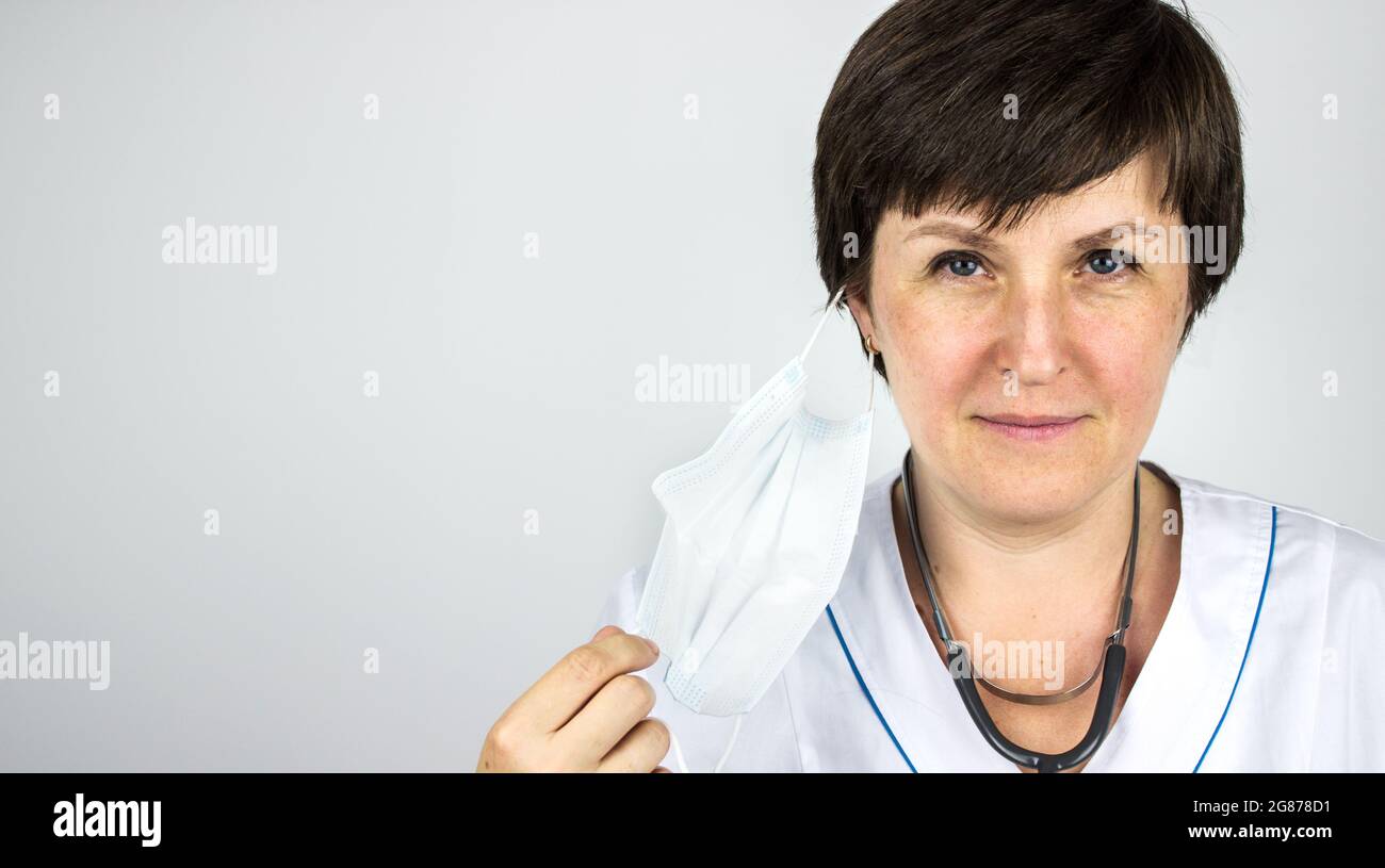 Concetto di blocco finale. Ritratto di un medico, rimozione della maschera chirurgica, primo piano. Pandemia, Covid-19, epidemia, concetto di coronavirus Foto Stock