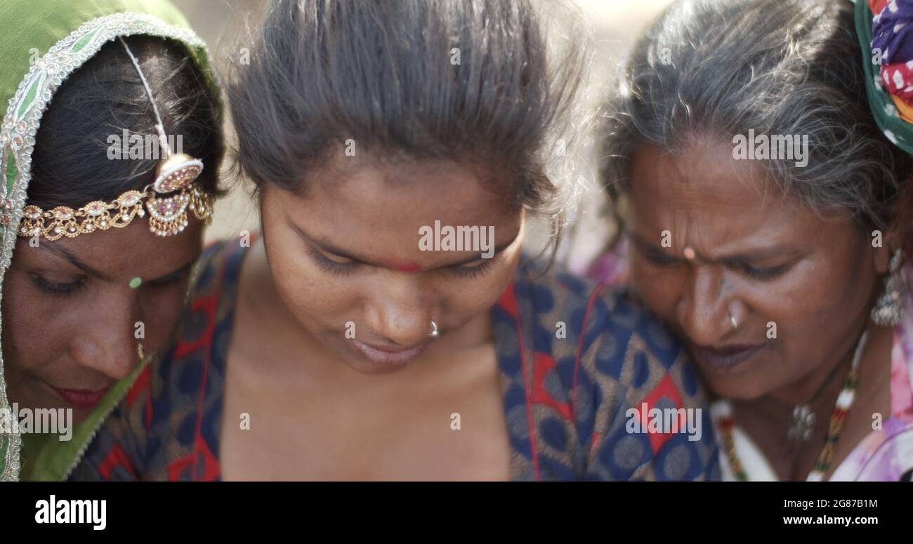 Gruppo di donne indiane in abbigliamento tradizionale guardando attentamente qualcosa Foto Stock