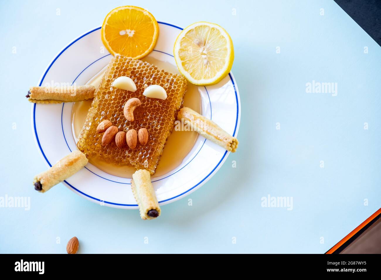 Sorriso faccia fatta dal miele alveare, mandorle, e eid kahk farcito con datteri su un piatto con lime e arancio Foto Stock