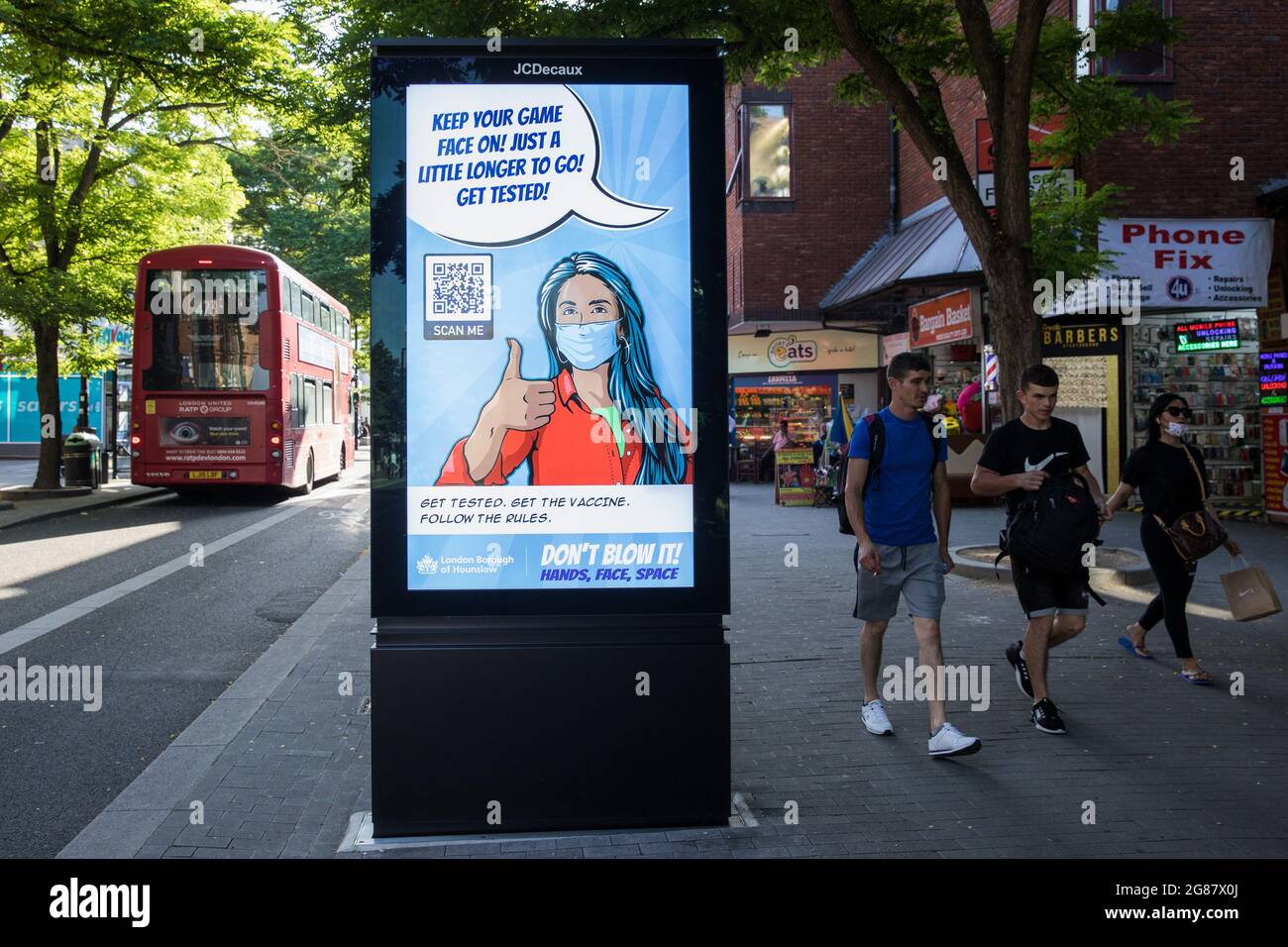 Londra, Regno Unito. 17 luglio 2021. I membri del pubblico passano un London Borough of Hounslow Covid-19 public information display che invita i residenti ad utilizzare i test e le strutture di vaccinazione tra le crescenti preoccupazioni per la diffusione della variante Delta. Il governo britannico dovrebbe ancora revocare quasi tutte le restrizioni sui contatti sociali il 19 luglio, noto come "Freedom Day", ma l'attuale ondata guidata dalla variante Delta non dovrebbe raggiungere il picco fino a metà agosto. Credit: Mark Kerrison/Alamy Live News Foto Stock