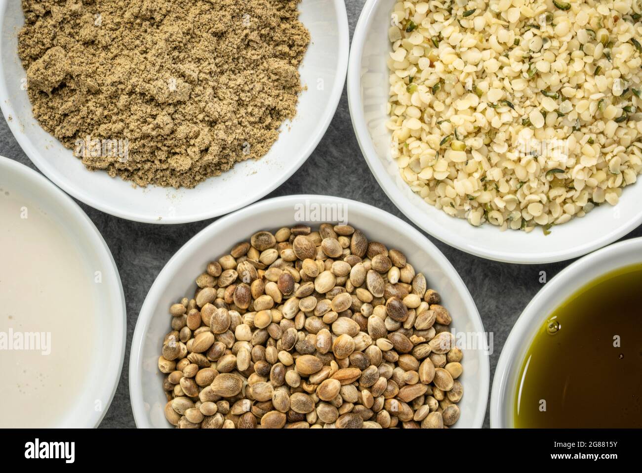 raccolta di prodotti di semi di canapa: cuori, proteine in polvere, latte e olio in piccole ciotole bianche, concetto di supercibo Foto Stock