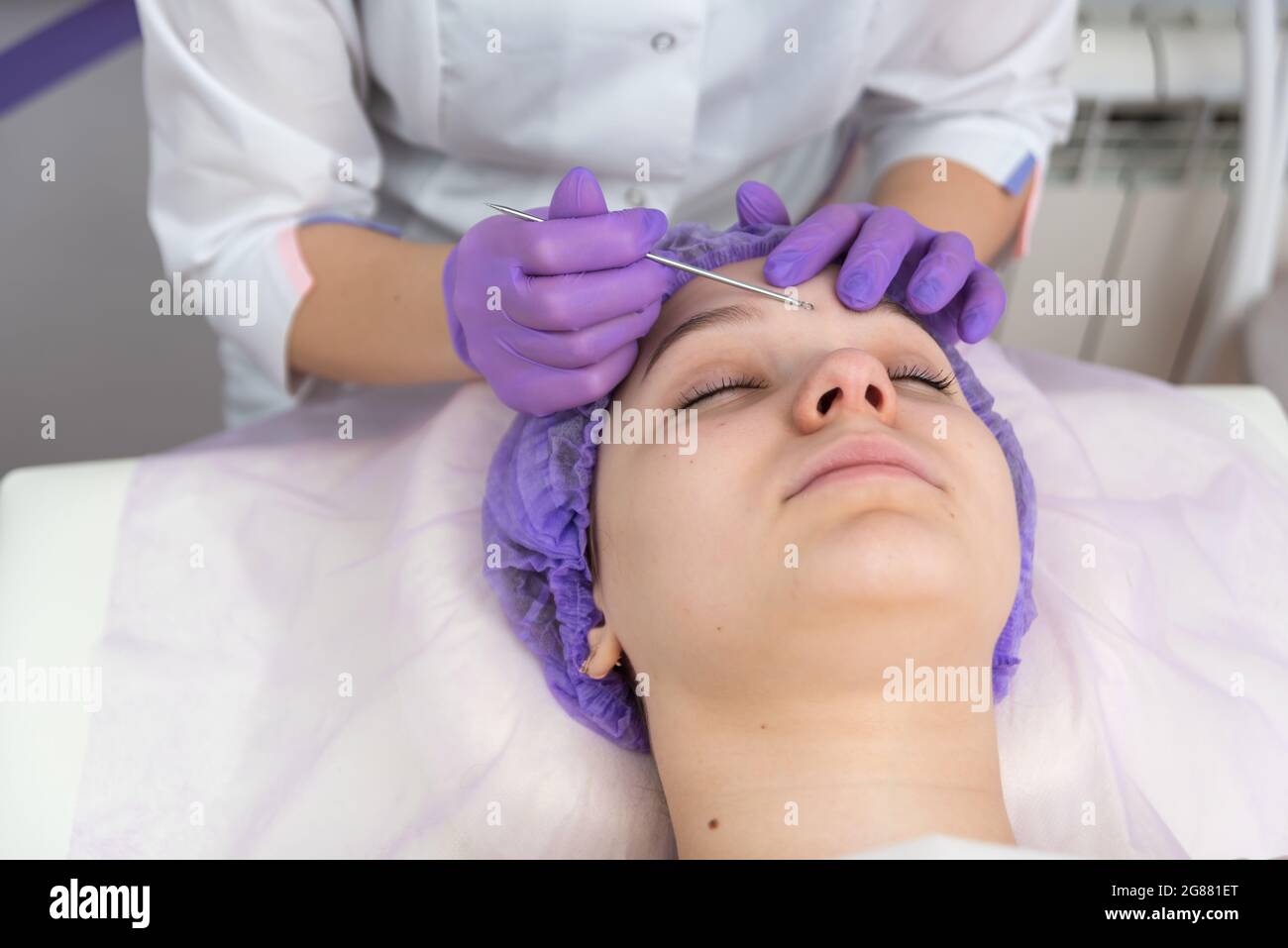 La cliente femminile sta avendo un trattamento facciale con l'aiuto del loop oculare. Cosmetologia e routine di cura della pelle. Foto Stock