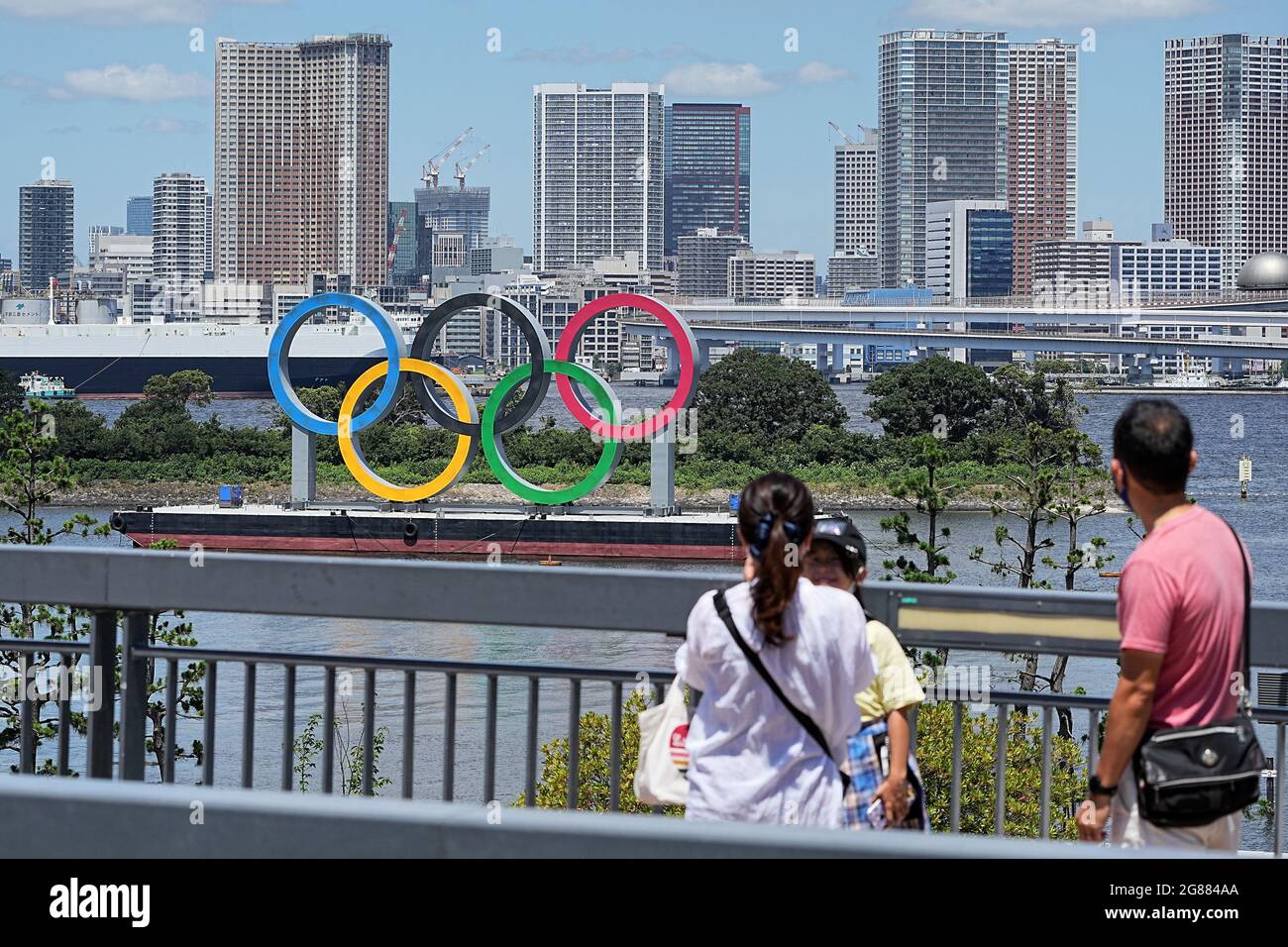 Tokio, Giappone. 18 luglio 2021. Una famiglia si trova di fronte agli Olimpiadi di grandi dimensioni. Gli anelli si ergono su una zattera nella Baia di Tokyo di fronte al quartiere di Odaiba. Le Olimpiadi di Tokyo 2020 si terranno dal 23.07.2021 al 08.08.2021. Credit: Michael Kappeler/dpa/Alamy Live News Foto Stock