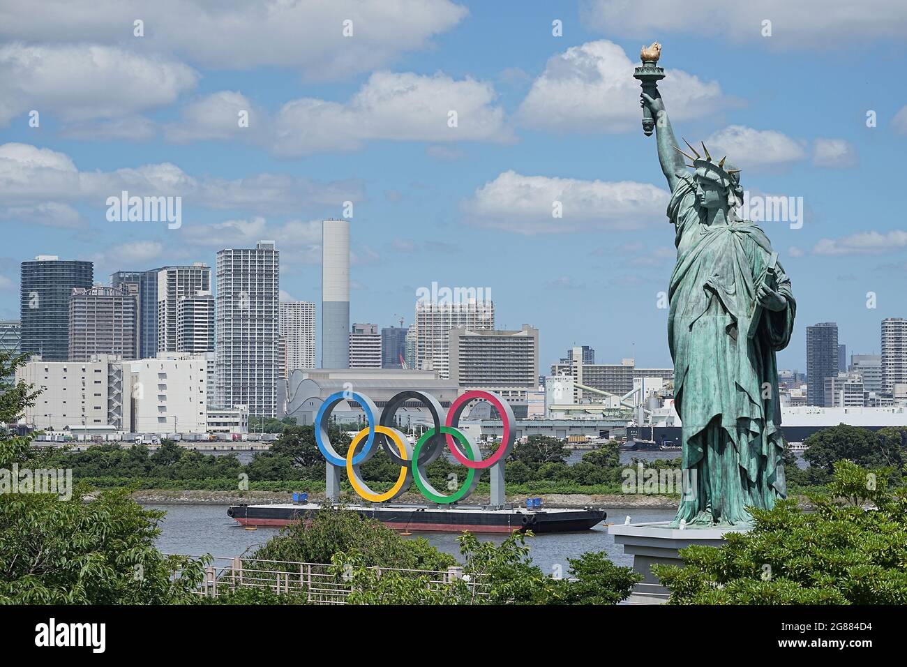 Tokio, Giappone. 18 luglio 2021. La Statua della libertà di Odaiba si trova di fronte ai grandi anelli olimpici. Gli anelli si ergono su una zattera nella Baia di Tokyo di fronte al quartiere di Odaiba. Le Olimpiadi di Tokyo 2020 si terranno dal 23 luglio 2021 all'8 agosto 2021. Credit: Michael Kappeler/dpa/Alamy Live News Foto Stock
