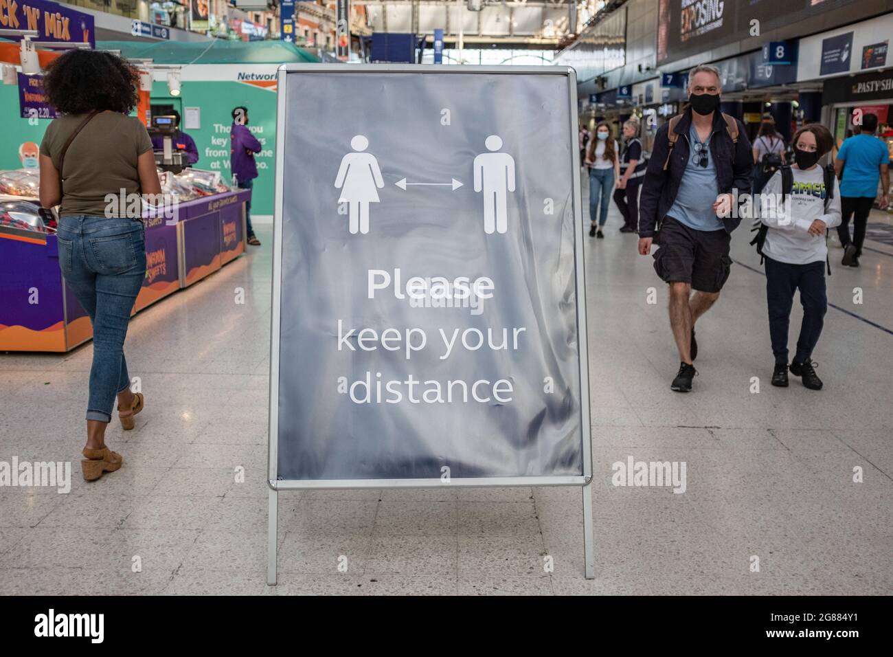 Londra, Regno Unito. 16 luglio 2021. Un cartello con la scritta 'si prega di mantenere la distanza e le persone che indossano maschere sono visti all'interno di una stazione della metropolitana di Londra. Il primo ministro Boris Johnson ha annunciato che l'Inghilterra si sposterà al quarto passo della roadmap del governo che sarà fuori blocco lunedì 19 luglio, con 'quasi tutte' le restrizioni COVID rimanenti che sono state revocate in questa data. (Foto di May James/SOPA Images/Sipa USA) Credit: Sipa USA/Alamy Live News Foto Stock