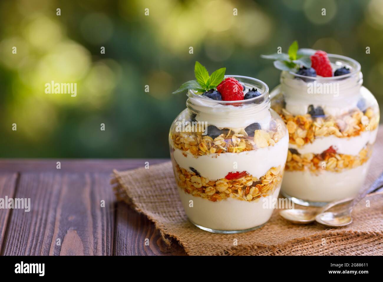 granola con yogurt greco e bacche in due vasetti di vetro Foto Stock