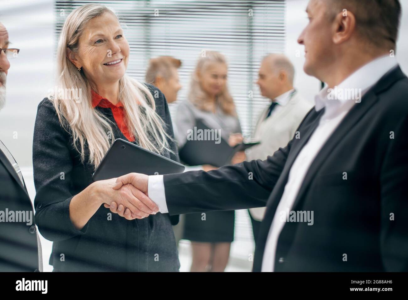 primo piano: due uomini d'affari che scuotono le mani nella hall dell'ufficio Foto Stock