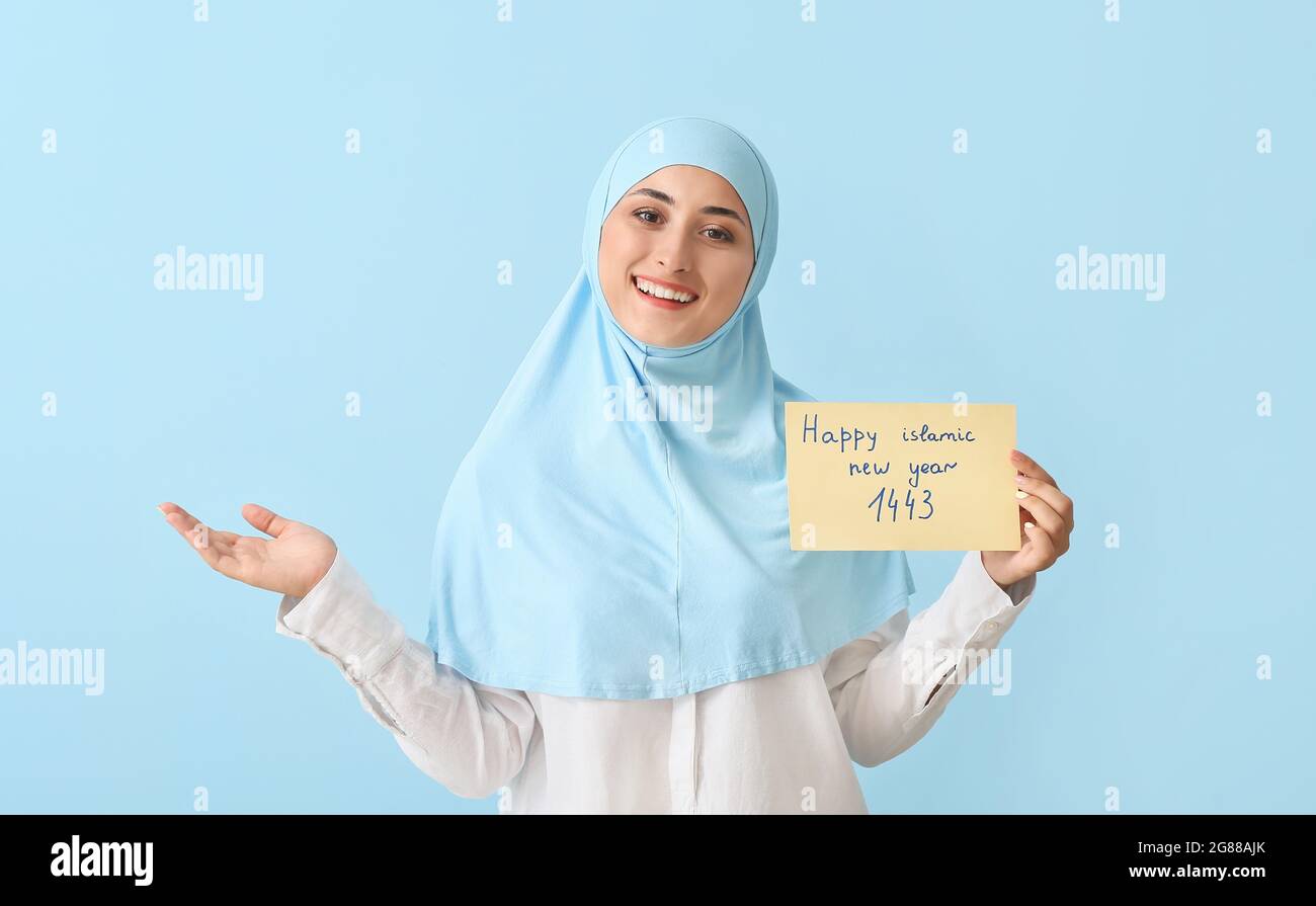 Giovane musulmana con biglietto di auguri per il nuovo anno Islamico su sfondo a colori Foto Stock