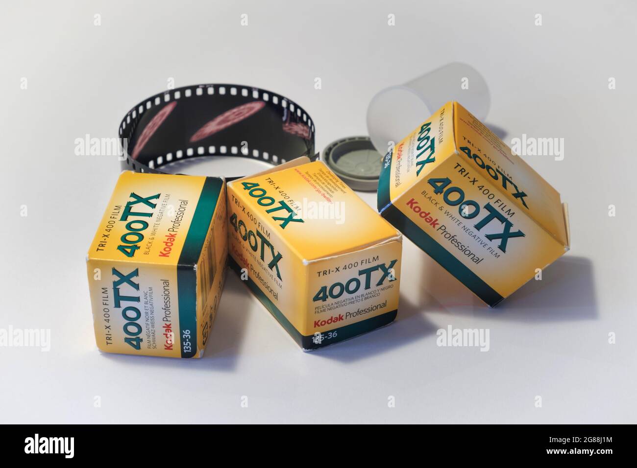 Apparecchiatura per la fotografia d'epoca con bobine di pellicola Kodak Tri-X 400 in pellicola bianca e nera e un rotolo di pellicola sviluppato su uno sfondo liscio Foto Stock