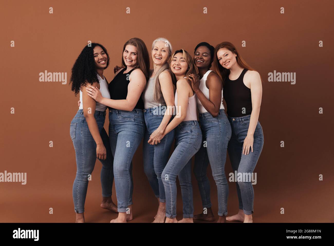 Sei donne di diverse età e tipi di corpo sorridenti e ridenti su sfondo marrone Foto Stock