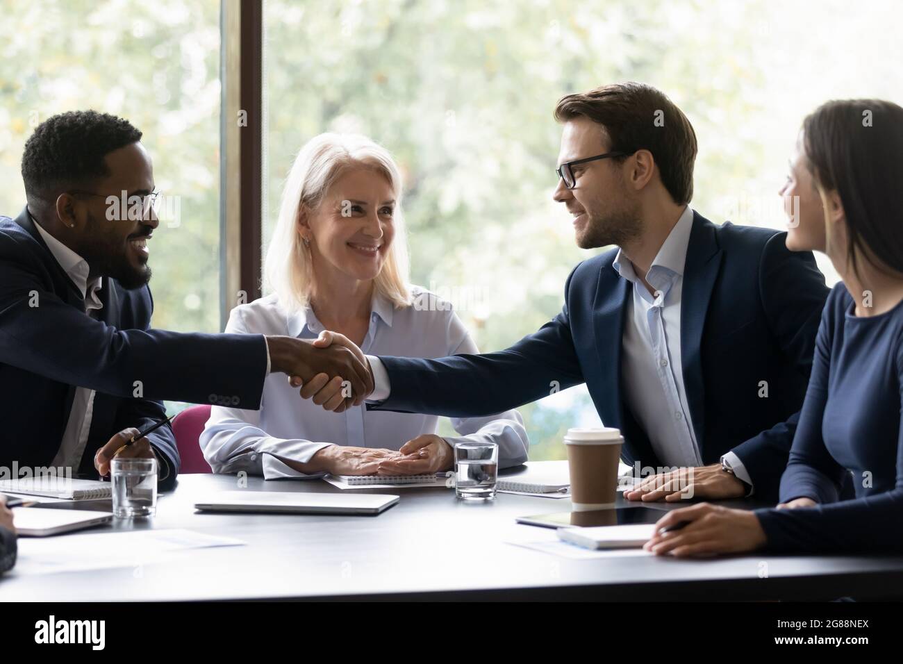 Felici i diversi partner commerciali che scuotono il tavolo delle mani Foto Stock