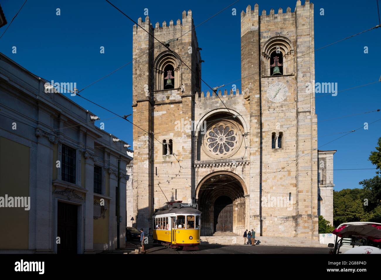 Lisbona, Portogallo - 16 luglio 2021: Vista della cattedrale di Lisbona (se de Lisboa) con un iconico tram giallo che passa di fronte, nella città di Lisbona Foto Stock