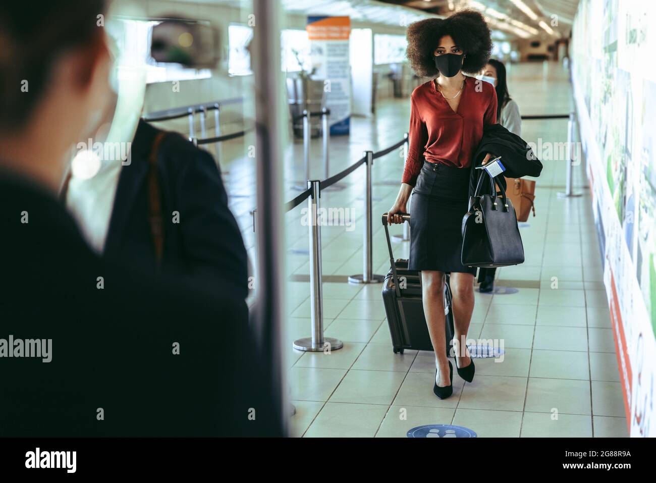 viaggiatori che camminano attraverso il checkpoint di scansione termica presso il terminal dell'aeroporto. Persone che attraversano i posti di blocco in aeroporto durante la pandemia. Foto Stock