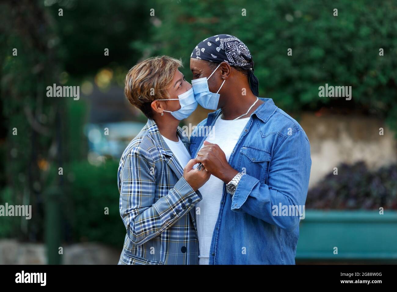 Coppia di amanti che indossano maschera protettiva bacia all'aperto - nuovo concetto di relazione normale con il fidanzato e fidanzata coperta da bacio facemask Foto Stock