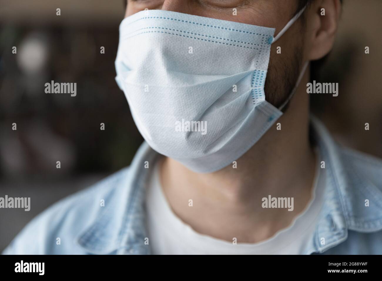 Primo piano giovane uomo che indossa maschera medica monouso. Foto Stock