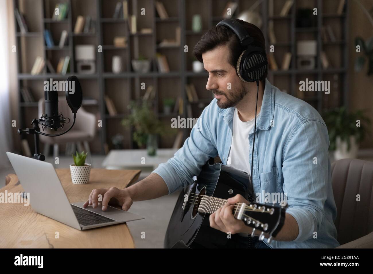 Felice giovane che suona la chitarra usando un'applicazione per computer. Foto Stock