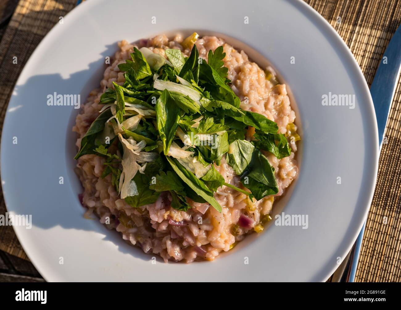 Cena estiva all'aperto sotto il sole: Carne di granchio e cipolla rossa risotto con finocchio rasato, basilico e prezzemolo Foto Stock