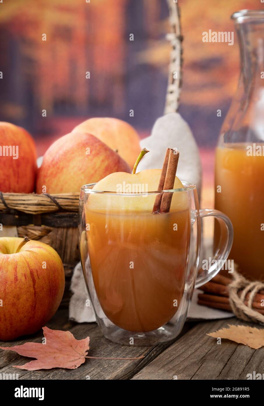 Primo piano di un bicchiere di sidro di mele e mele fresche su un rustico tavolo in legno con sfondo autunnale Foto Stock