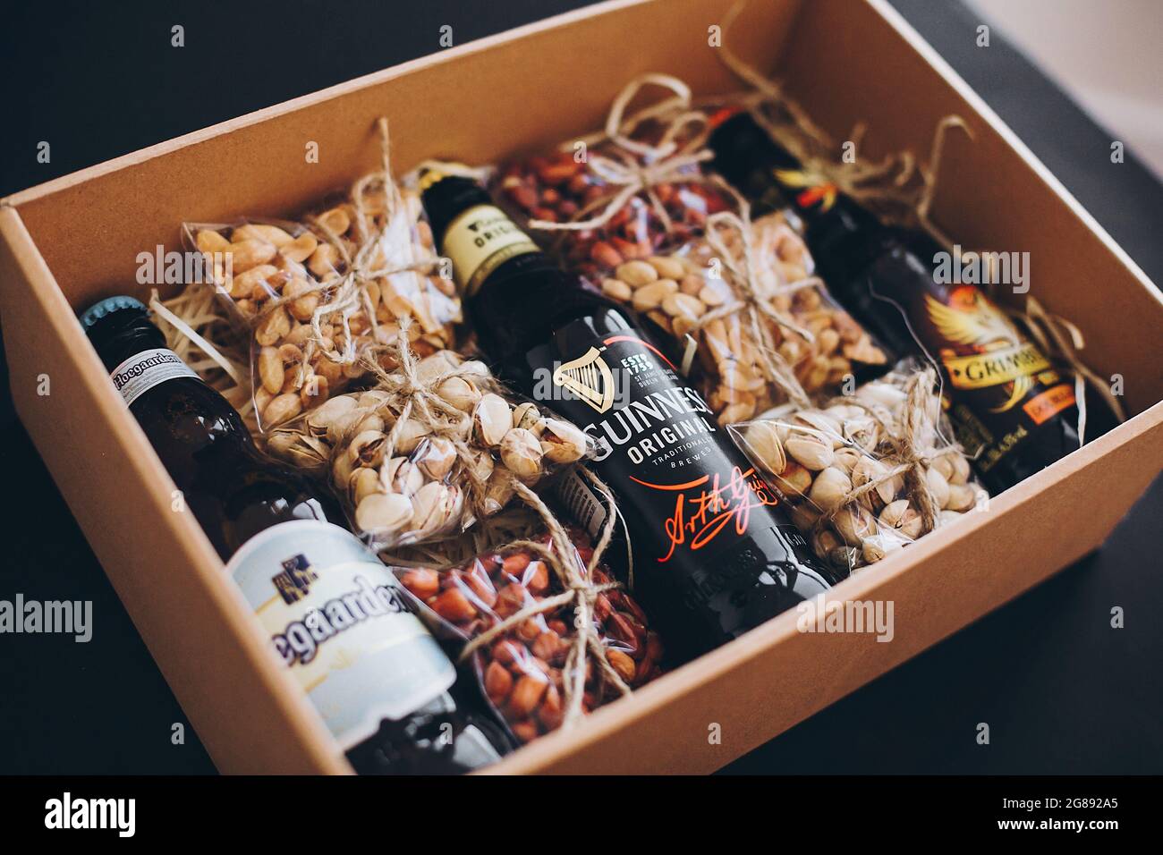 Lviv, Ucraina - 1 dicembre 2017: Bottiglie di birra Hoegaarden, Grimbergen e Guinness con etichetta e spuntini di noci salate sulla paglia in scatola regalo. GIF elegante Foto Stock