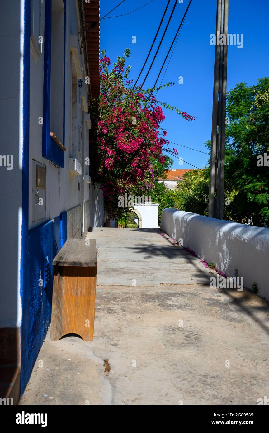 C'è una piccola panchina di fronte ad una tipica casa portoghese decorata con molti fiori. Foto Stock