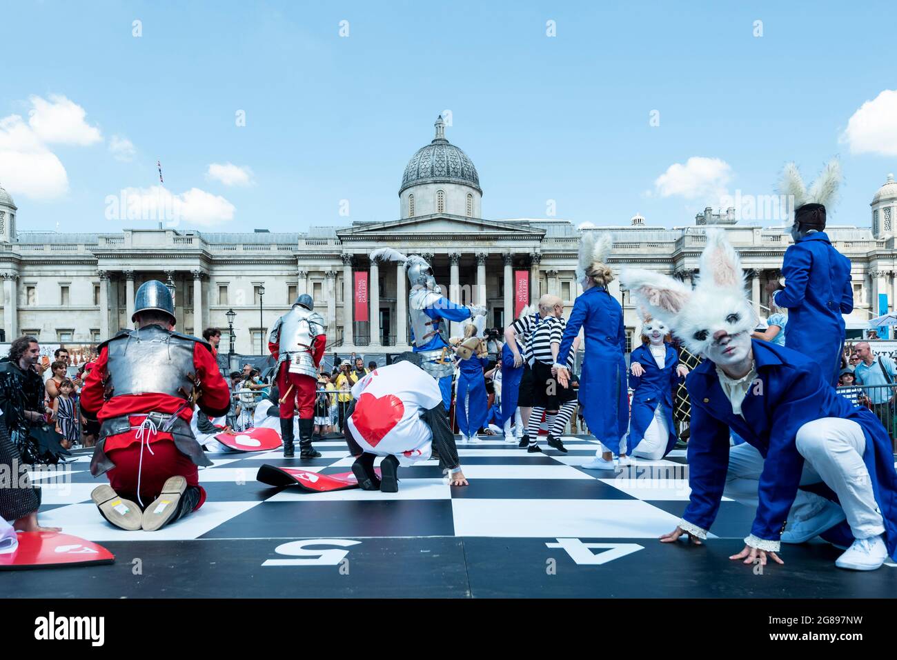 Londra, Regno Unito. 18 luglio 2021. Gli attori in costume prendono parte a una partita di scacchi umani al Chess Fest in Trafalgar Square. L'evento celebra il gioco degli scacchi e i visitatori possono imparare il gioco, giocare a scacchi o sfidare un Gran Maestro. Inoltre, per celebrare il 150° anniversario di Alice di Lewis Carroll attraverso il libro Looking Glass che ha presentato il gioco degli scacchi, 32 attori vestiti da Alice attraverso i personaggi Looking Glass si trovano su una scacchiera gigante che riproduce un gioco basato sul libro. Credit: Stephen Chung / Alamy Live News Foto Stock