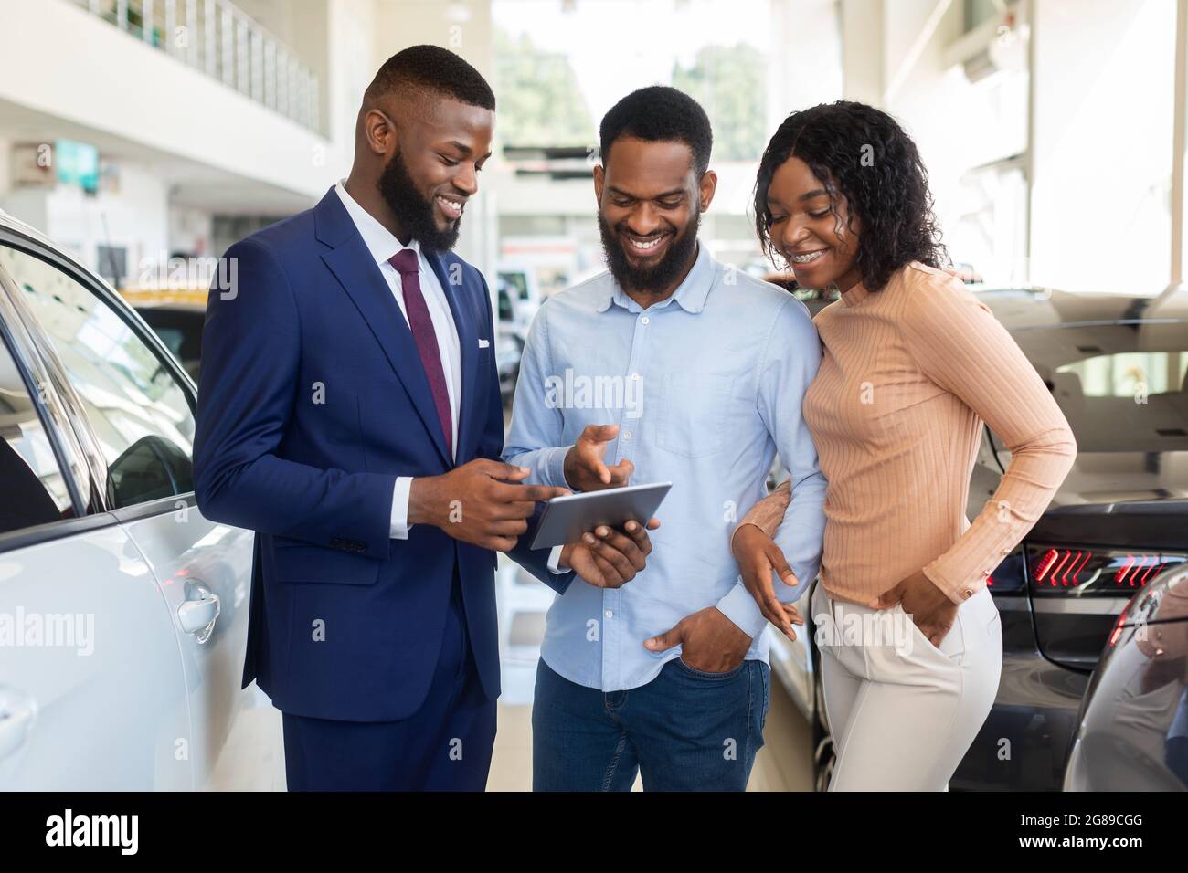 Bel venditore di auto che mostra i dettagli di acquisto su Digital Tablet a Black Couple Foto Stock