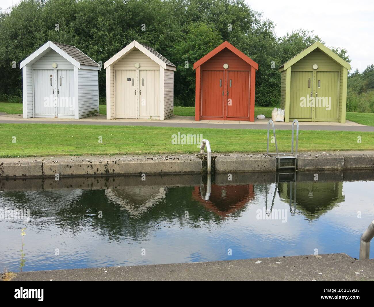 Una fila di quattro capannoni dai colori vivaci per i proprietari di imbarcazioni presso il porticciolo di Kelpies, Helix Park, Falkirk, Scozia. Foto Stock