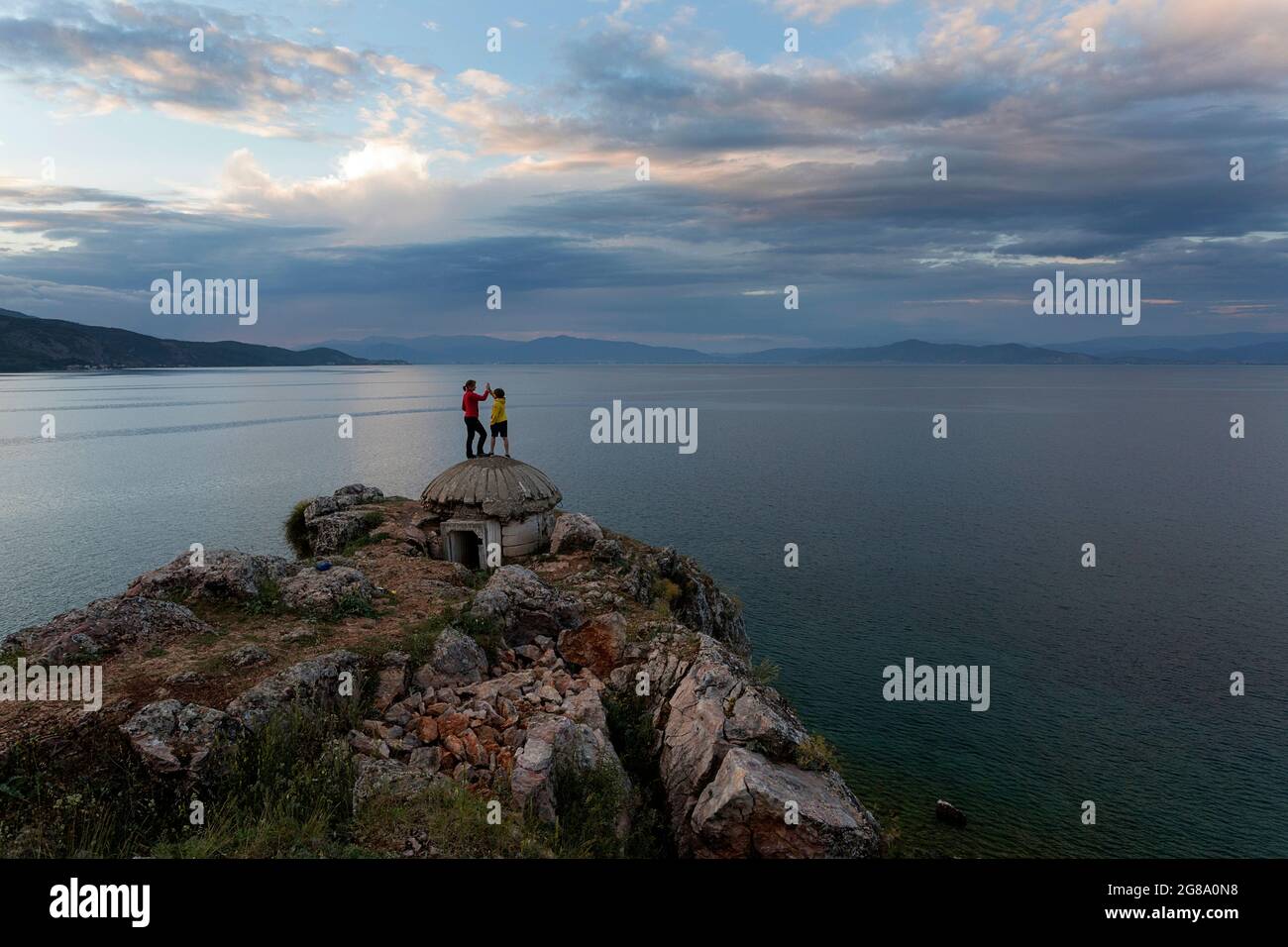 Ragazzo che dà alto cinque a madre su vecchio bunker al lago Ohrid, vicino Lin, regione di Korca, Albania Foto Stock