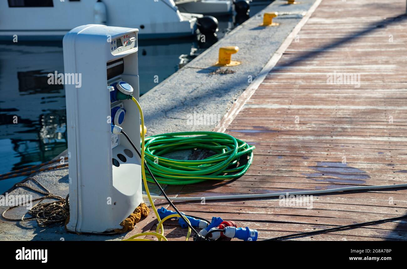 Grecia. Prese elettriche di carica per le navi nel porto. Stazione di approvvigionamento di Marina, energia elettrica e acqua per le navi ormeggiate al molo, spazio di copia. Myko Foto Stock