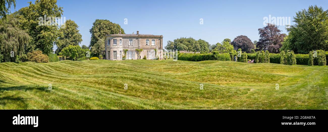 Insolito prato ondulato di fronte all'ala georgiana di Corsley House, Corsley, Wiltshire, Regno Unito il 18 luglio 2021 Foto Stock