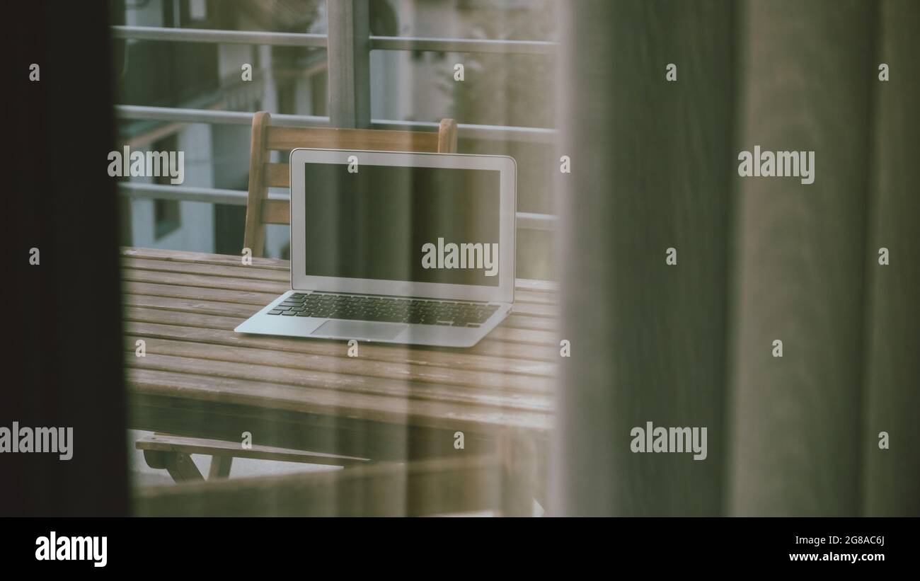 Computer portatile spento sul balcone della camera dell'hotel visto attraverso la finestra della camera, lavorando sul concetto di vacanza, fuoco selettivo Foto Stock