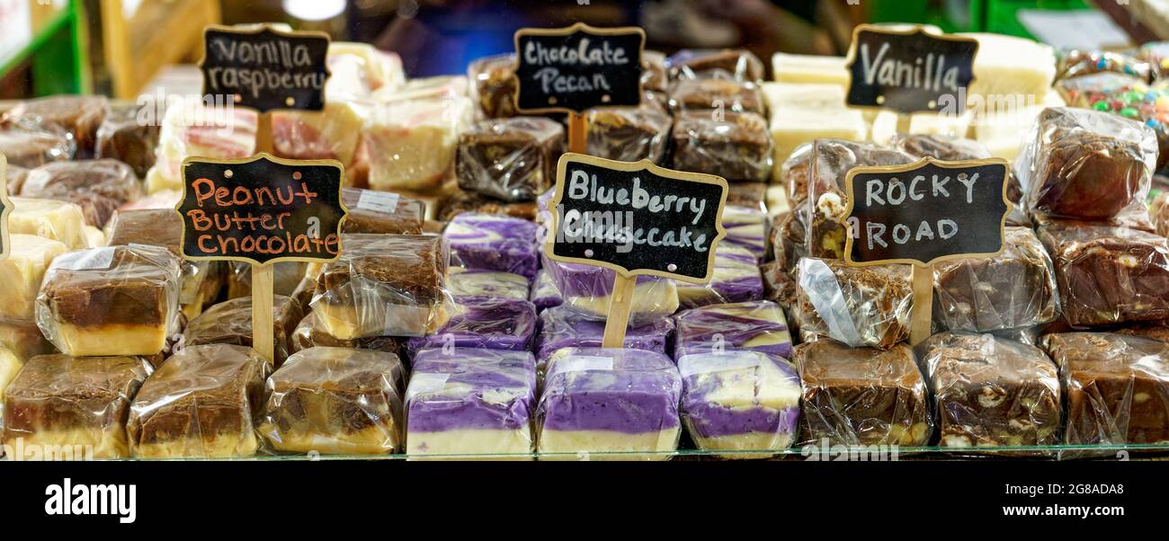 striscione di molti sapori di fudge avvolto in plastica con segni dietro il vetro Foto Stock