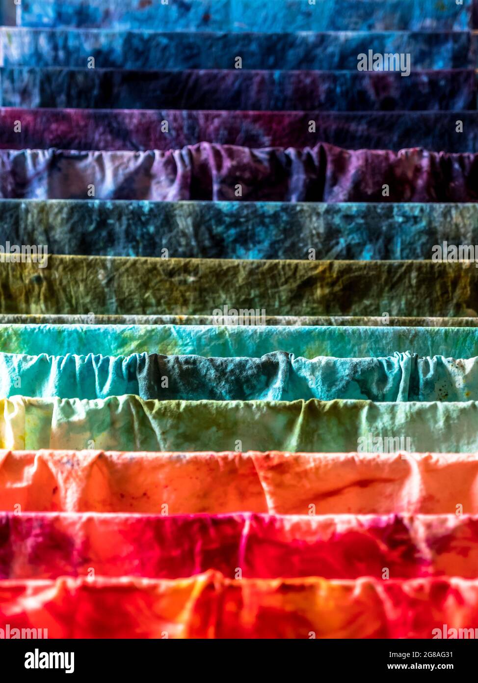 Closeup di vari colori tessuti di cotone umido tinti a mano che asciugano su un asciugatore Foto Stock