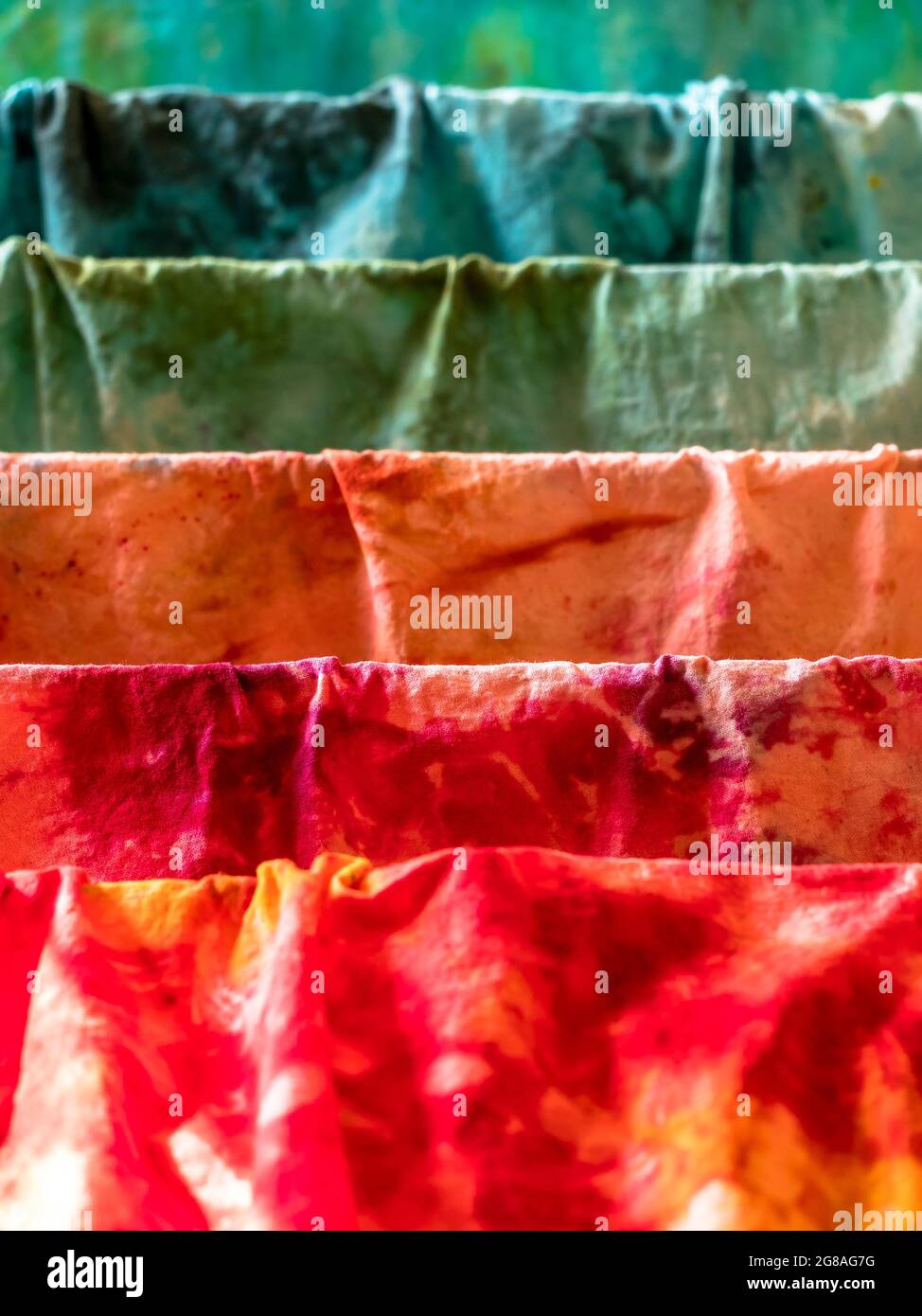 Closeup di vari colori tessuti di cotone umido tinti a mano che asciugano su un asciugatore Foto Stock