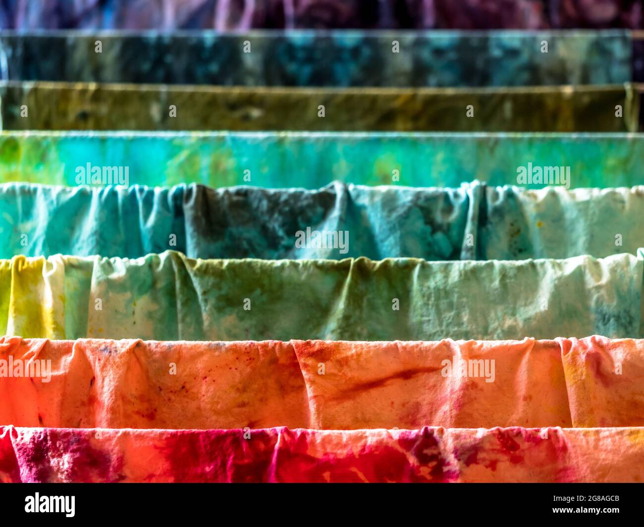 Closeup di vari colori tessuti di cotone umido tinti a mano che asciugano su un asciugatore Foto Stock