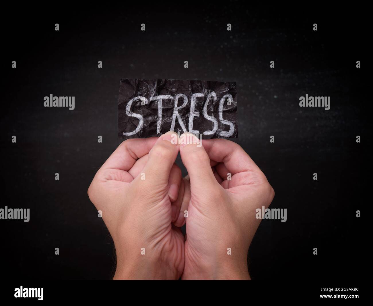 Una persona che tiene un pezzo di carta nero con la parola stress su di esso nelle sue mani. Primo piano. Foto Stock