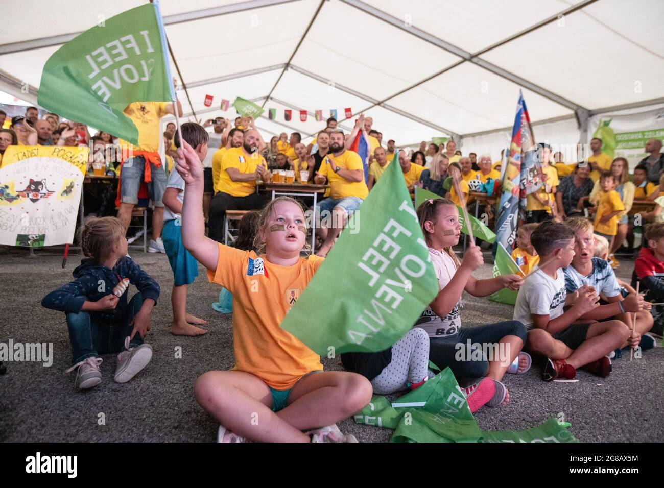 Komenda, Slovenia. 18 luglio 2021. I fan guardano una proiezione pubblica della fase finale del Tour de France durante una celebrazione pubblica della seconda vittoria di Tadej Pogacar nella sua città natale di Komenda, Slovenia. Centinaia di tifosi del ciclista sloveno Tadej Pogacar hanno celebrato la sua seconda vittoria consecutiva del Tour de France in una proiezione pubblica della tappa finale nella sua città natale di Komenda, Slovenia, dove hanno anche decorato la rotonda della città e la hanno dipinta di giallo. Credit: SOPA Images Limited/Alamy Live News Foto Stock