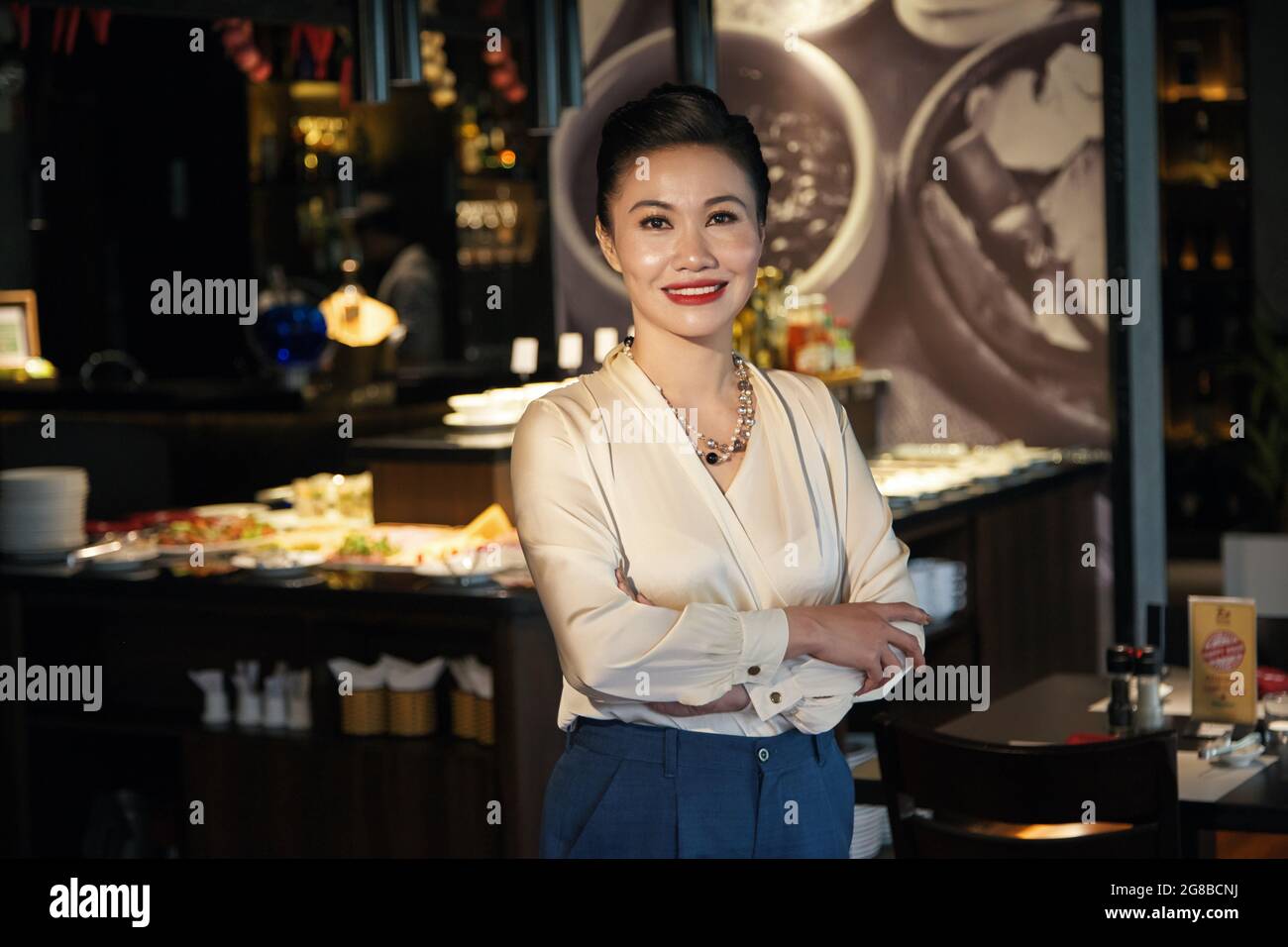 Ritratto di felice sorridente elegante donna di mezza età in piedi al banco bar del ristorante che sta aprendo Foto Stock