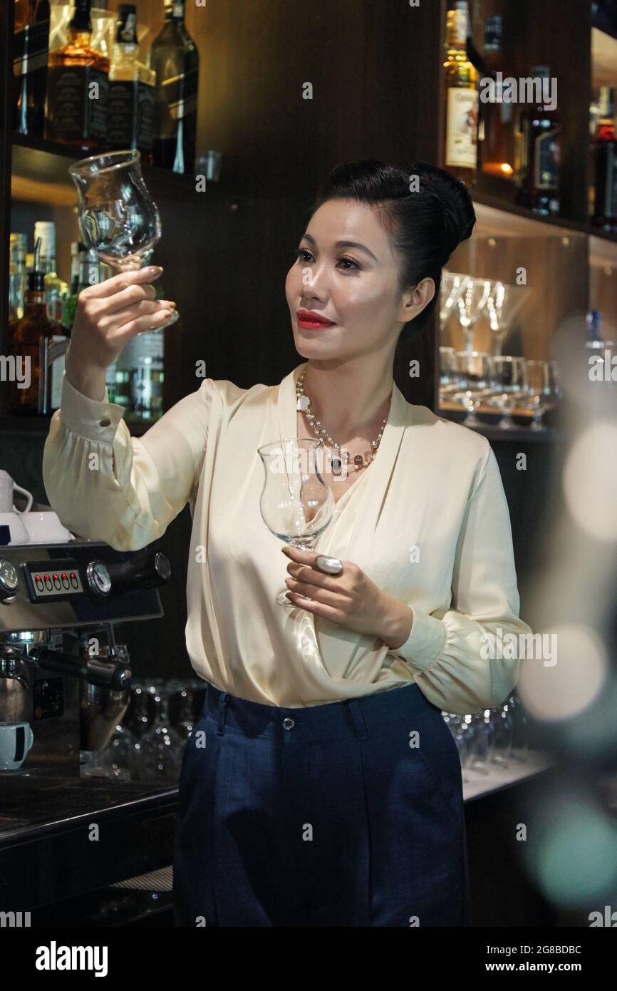 Elegante proprietario di un ristorante femminile che controlla i bicchieri di vino al bar Foto Stock