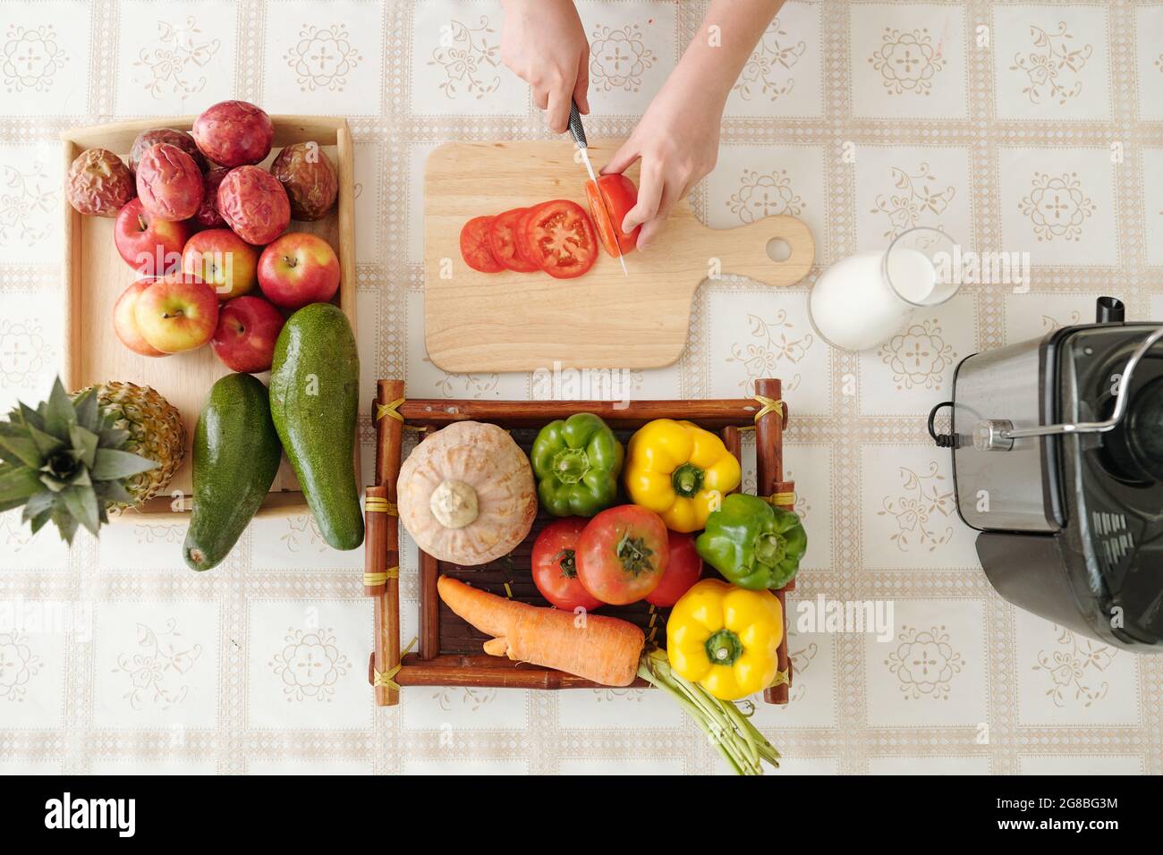 Casalinga affettando il pomodoro al tavolo da cucina quando cucinano un delizioso piatto per la cena in famiglia, vista dal tp Foto Stock