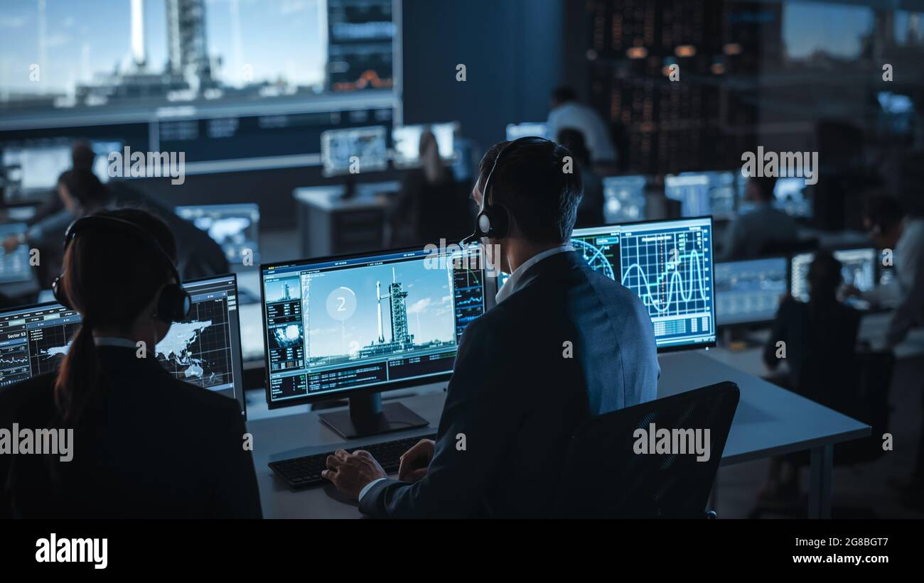 Gruppo di persone nel Mission Control Center testimone spazio lancio razzo. I dipendenti del controllo di volo si trovano sui display del computer anteriore e monitorano il personale Foto Stock