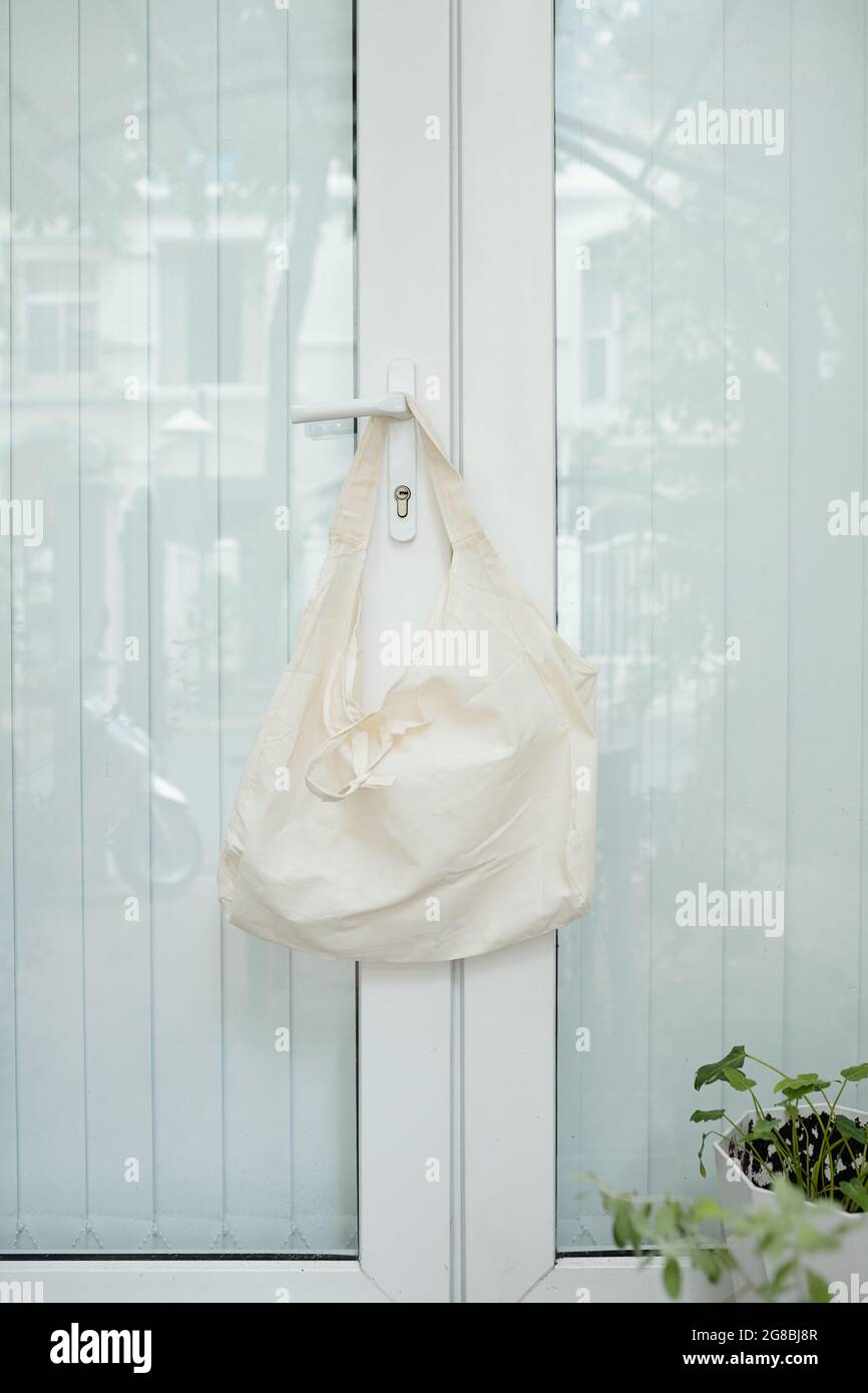 Borsa in tessuto riutilizzabile appesa al gancio della porta d'ingresso, riciclaggio e concetto di shopping sostenibile Foto Stock