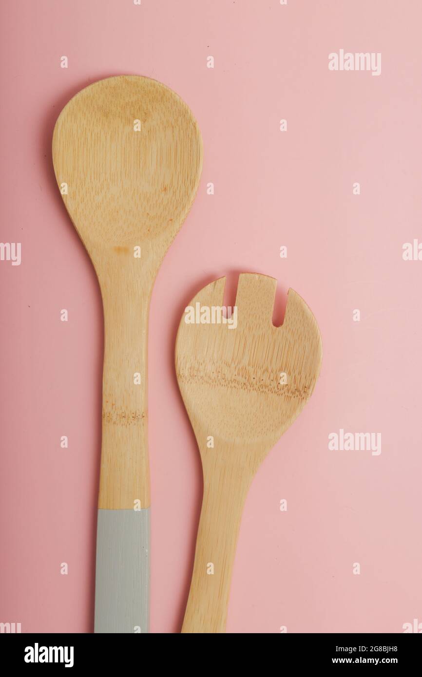set di cucchiai da cucina in legno su sfondo rosa Foto Stock