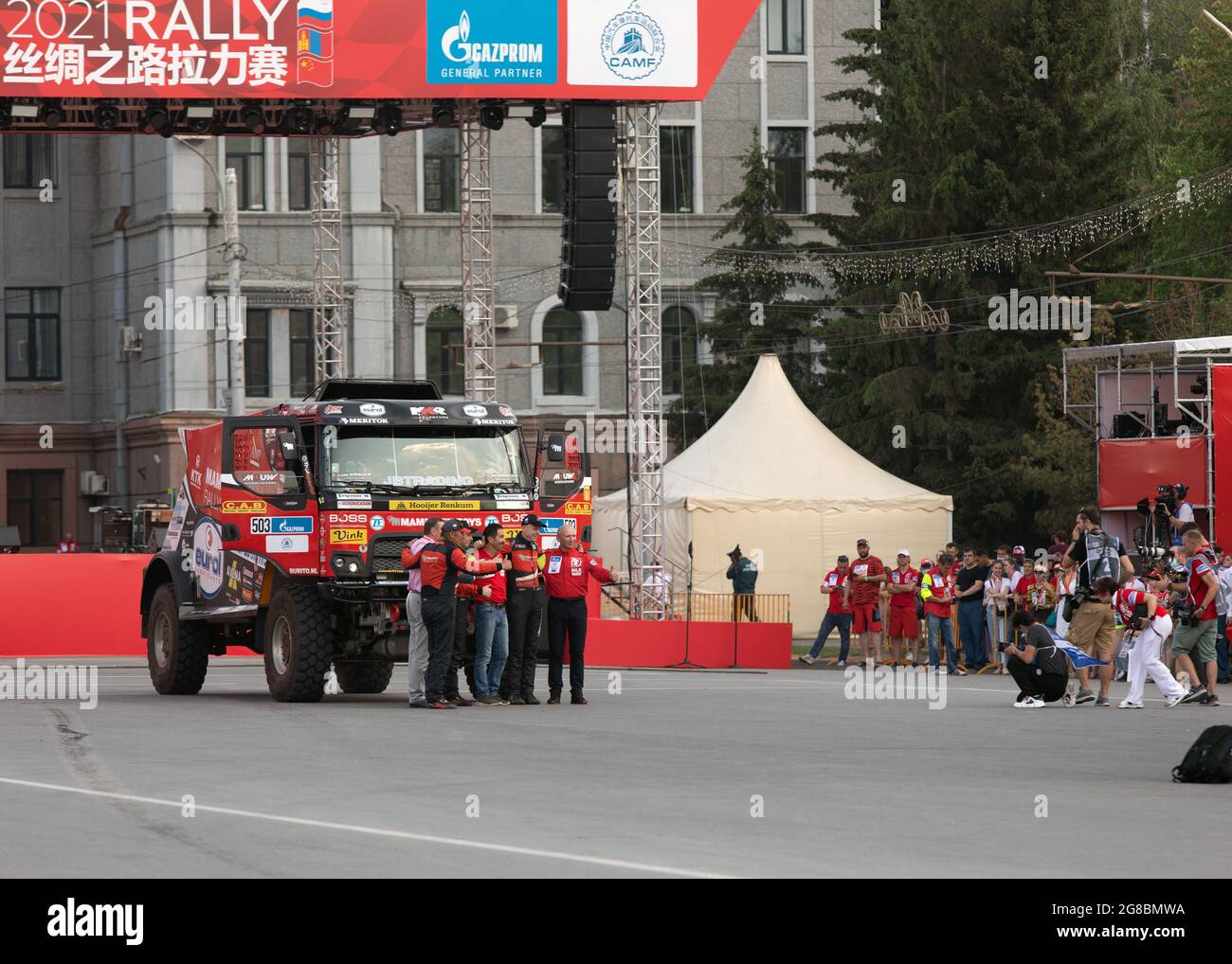 Gruppo di giornalisti scatta foto dei partecipanti alle competizioni sportive accanto all'auto all'aperto. Rally internazionale raid Via della Seta. Russia, Omsk, 01.07. Foto Stock