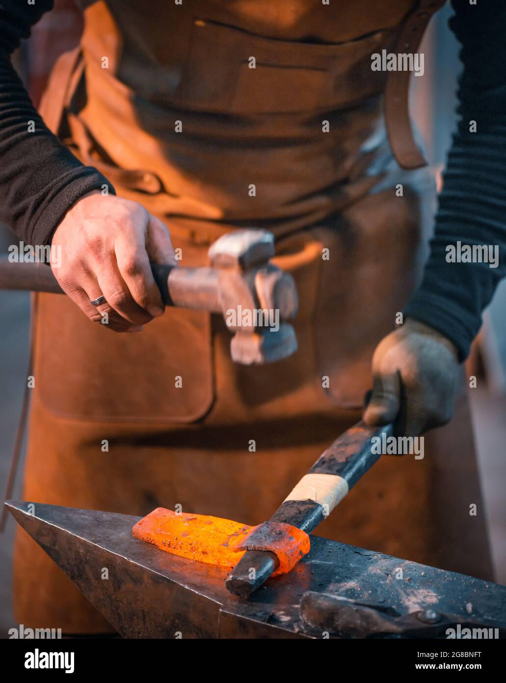 Il fabbro forgia un bianco di metallo rosso-caldo. Foto Stock