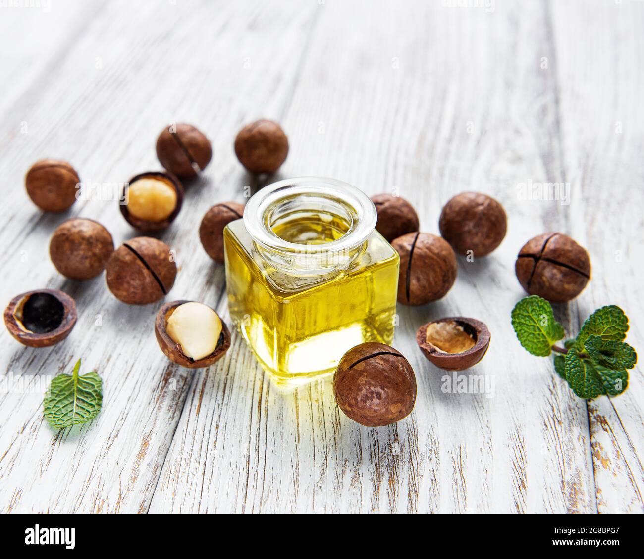 Olio di macadamia naturale e noci di Macadamia su tavola di legno Foto Stock
