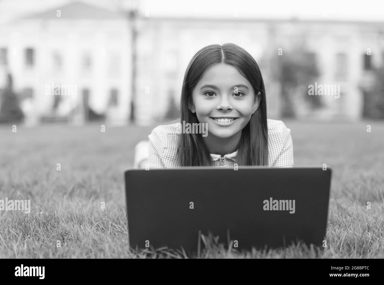 bambino imparare lezione privata. blogging. ragazza felice seduta su erba verde con laptop. Avvio. Bambino che gioca al computer. Torna a scuola. Istruzione Foto Stock