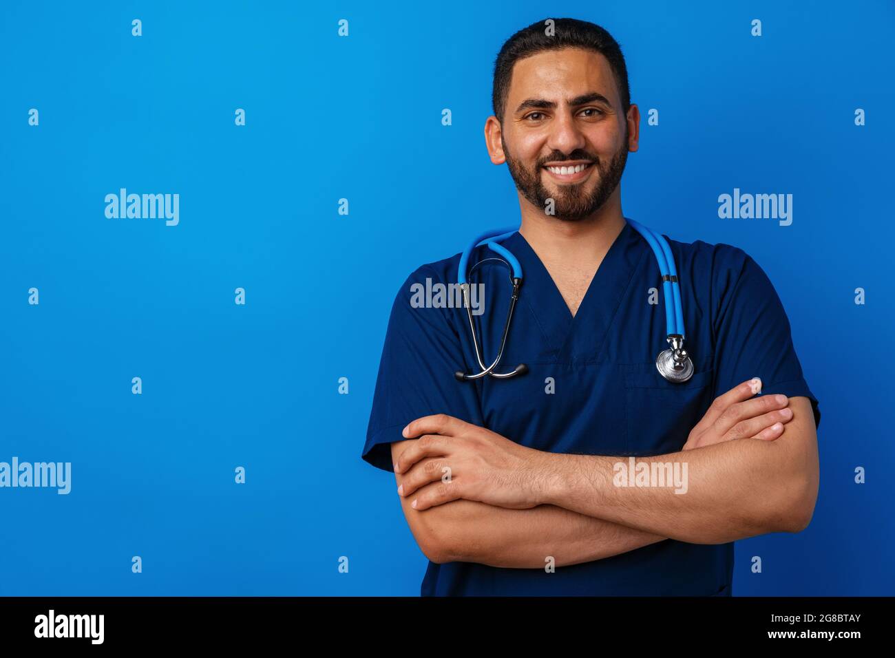 Bel giovane medico maschile in uniforme blu con stetoscopio su sfondo blu Foto Stock